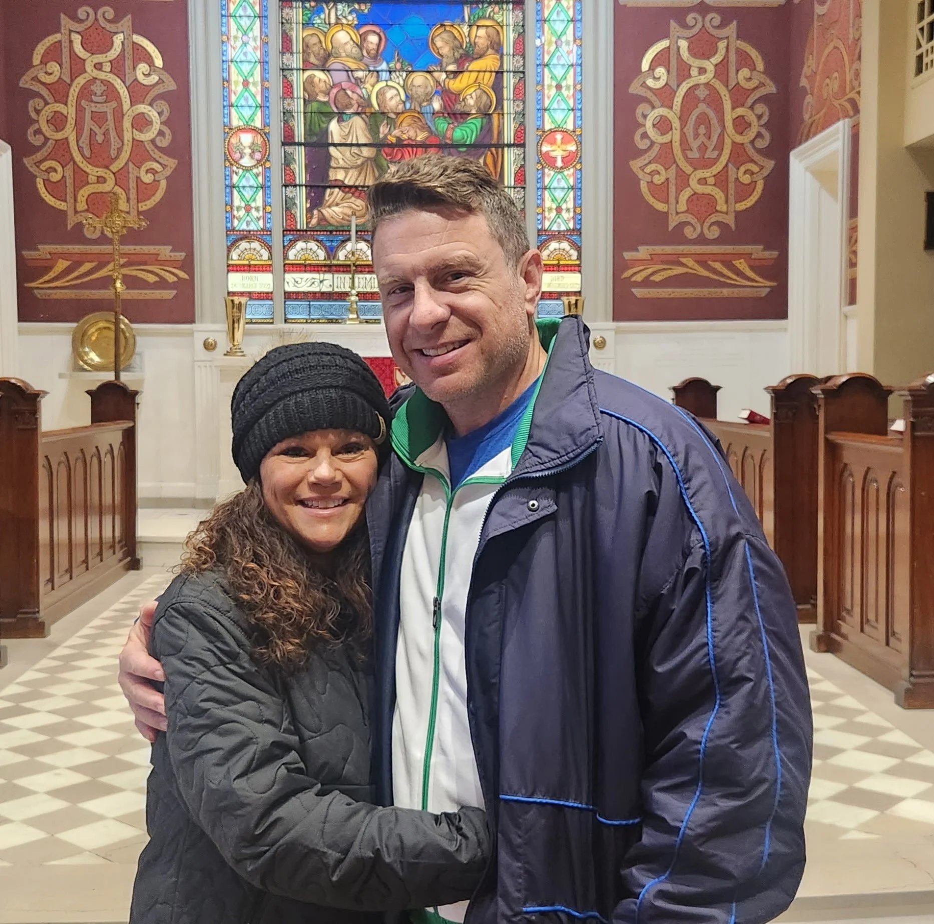A smiling couple hugging inside a church.